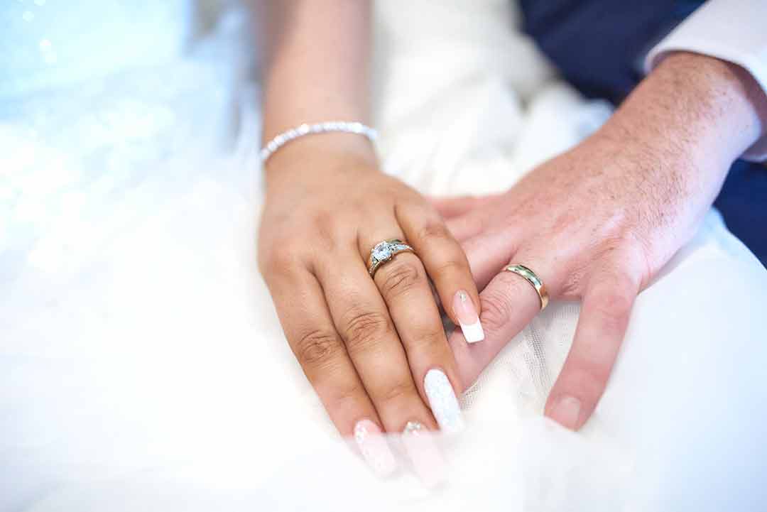 Bride and grrom holding hands showing off their wedding rings