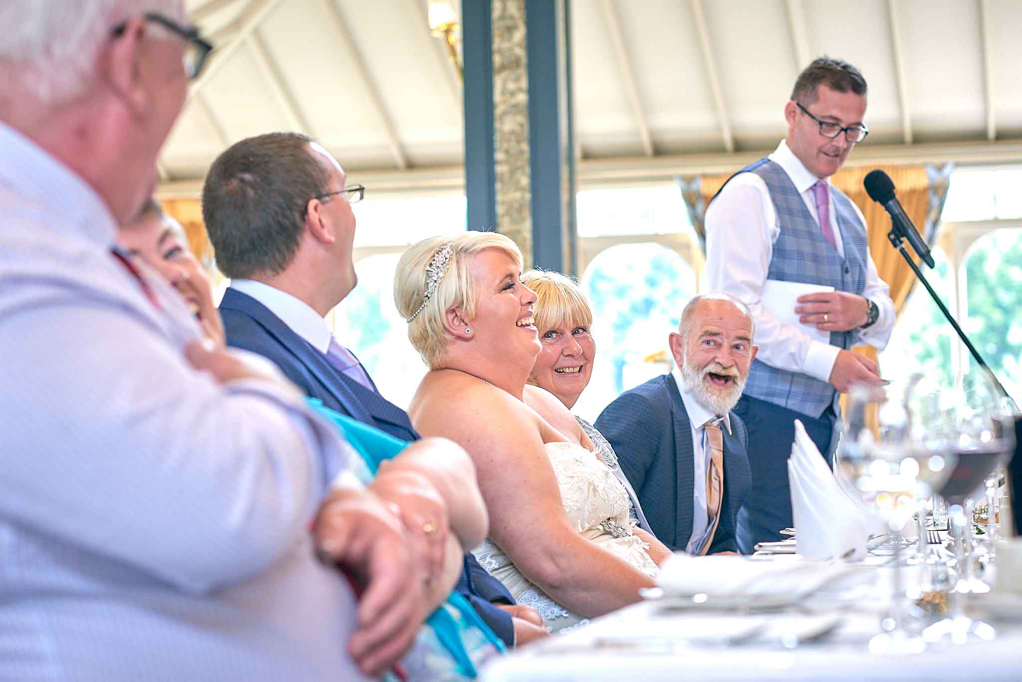 bride laughs as the best man says something funny during the speeches.