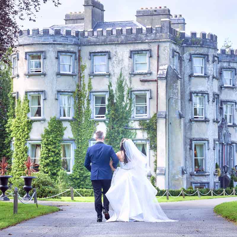 bride and groom walk towards Ballyseede castle hotel on their wedding day