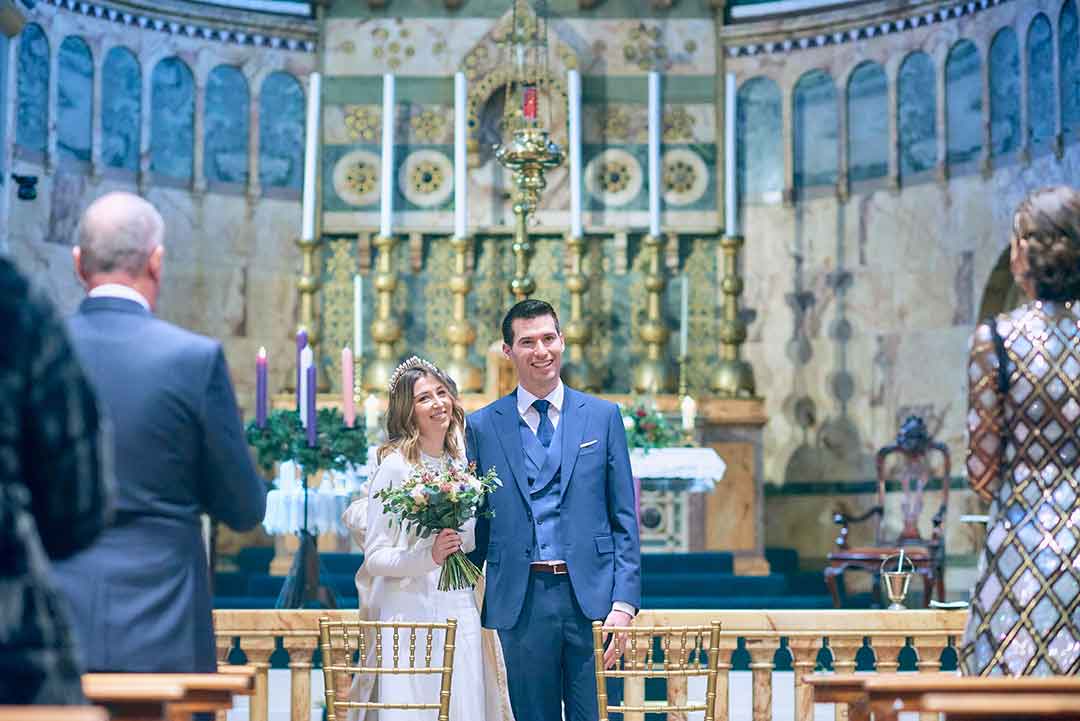 bride and groom smiling at their guests at the top of the alter in Newman church