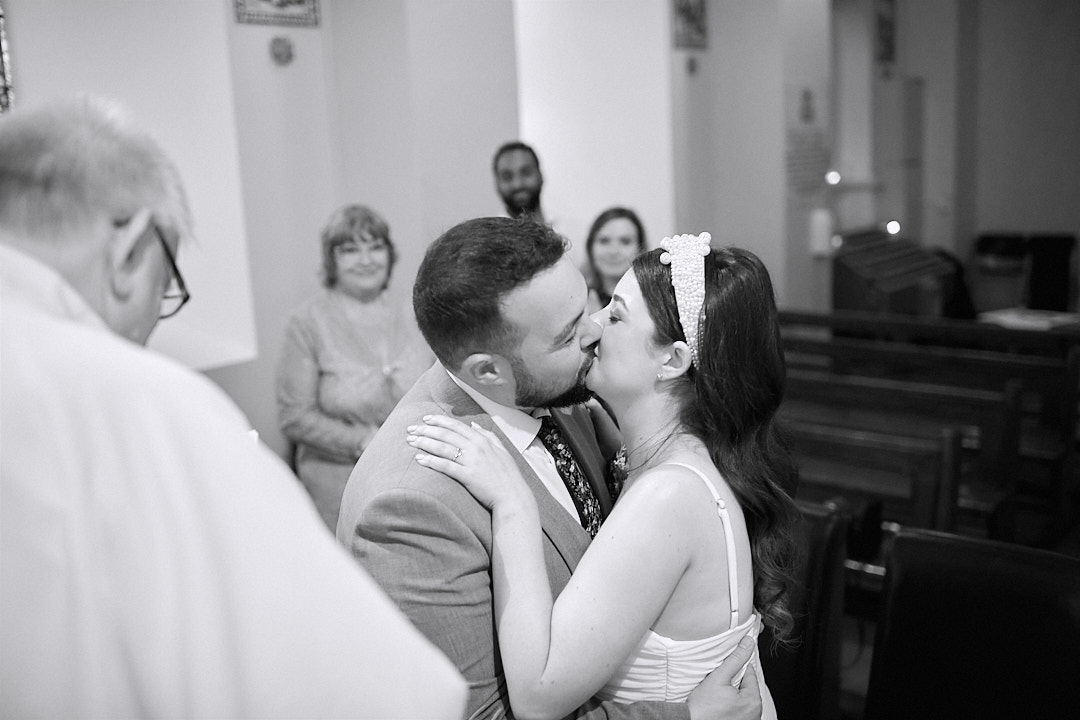 Bride and groom kiss at the alter getting married in Gouganne Barra church. 3 guests stand behind them