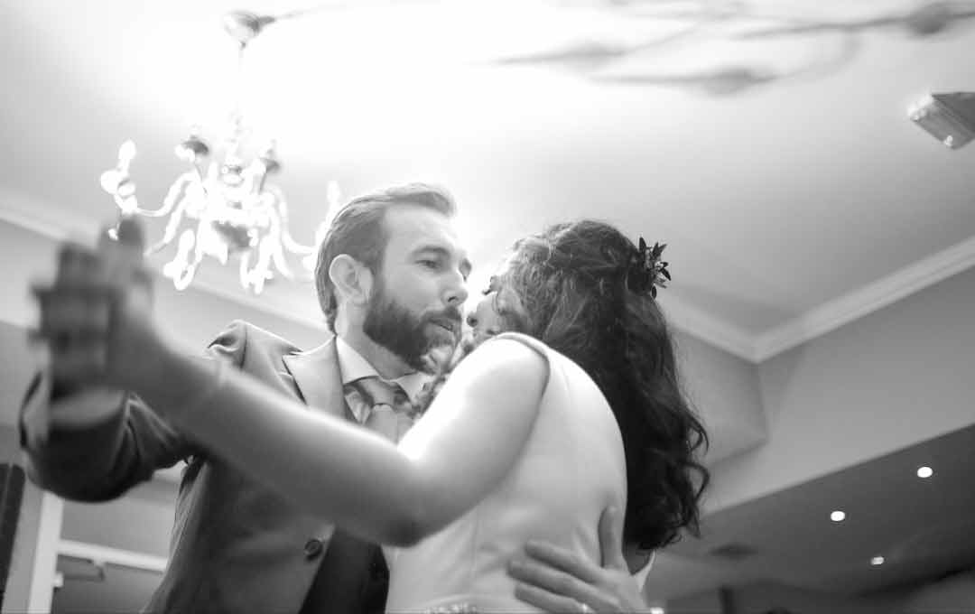 Bride and groom dancing arm in arm during their first dance